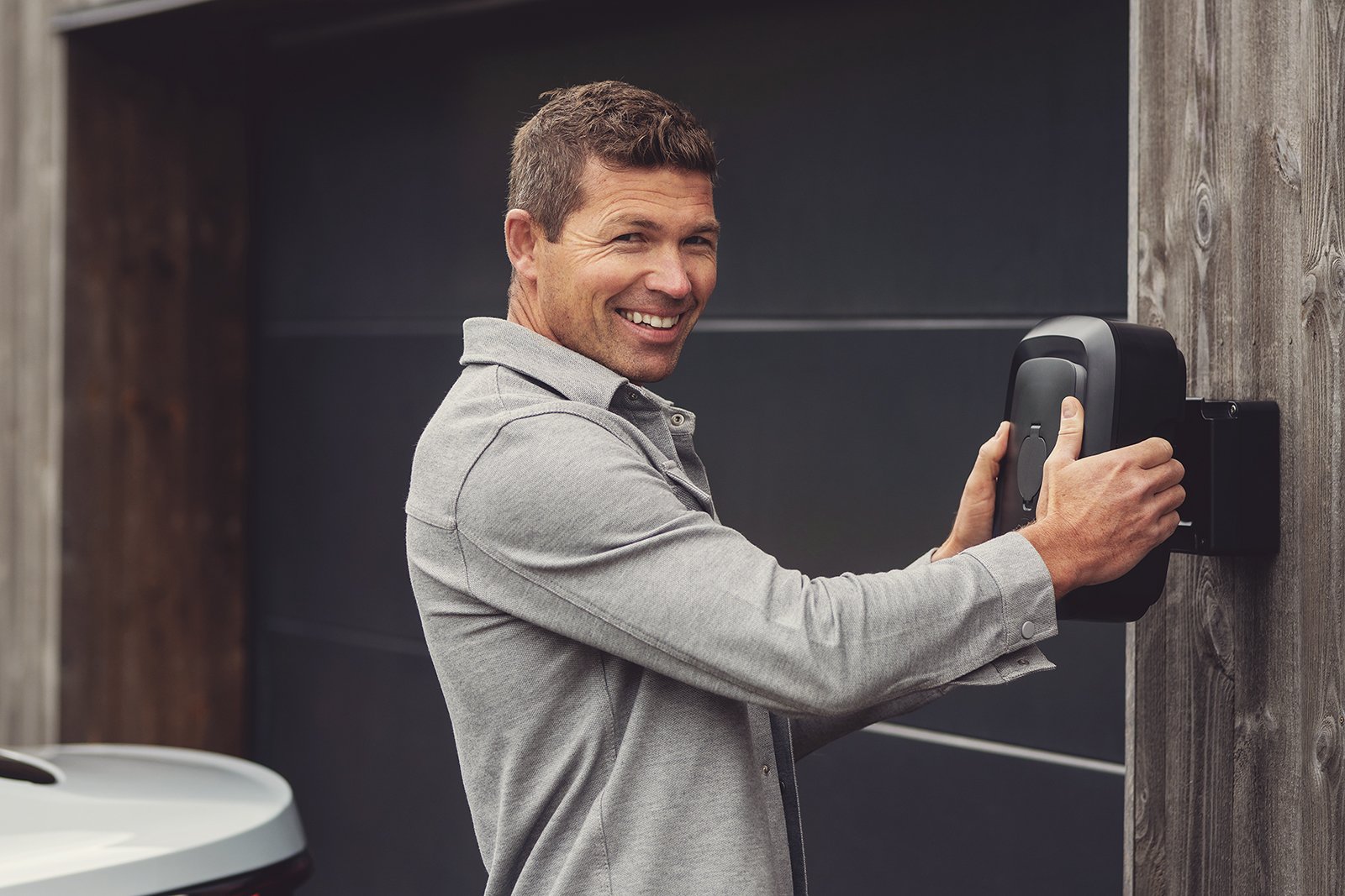 A person clipping an Enua Charge onto its wall-mounted Wallmount